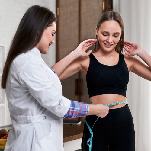 A nutritionist in his office measures the volume of his patient's waist
