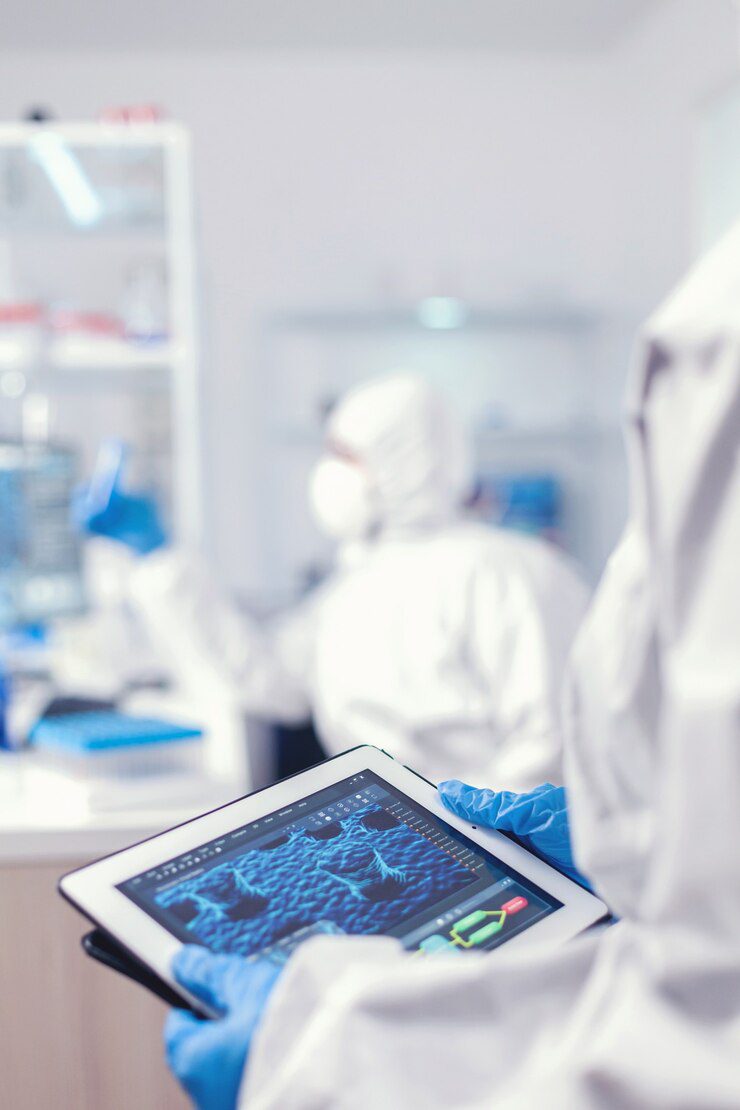 Chemist dressed in protection suit for coronavirus holding tablet pc in laboratory