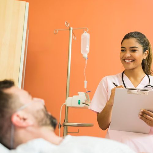 Smiling female doctor talking to male patient while reading reports at hospital